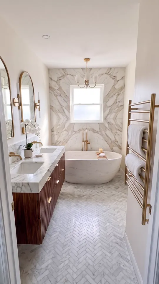 Finished marble and walnut bathroom with freestanding tub and arched gold mirrors